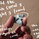 This is the third photo of a hand holding a plastic rock. It's bluish in color. There's handwriting over the photo that reads: "Behold the bluish coral I thought I found. It had rounded edges like polyps in coral. The color added to the illusion."